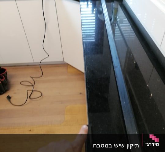 שיש שחור במטבח עם יד מצביעה עליו